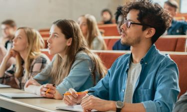 In the Classroom Multi Ethnic Students Listening to a Lecturer and Writing in Notebooks. Smart Young People Study at the College.