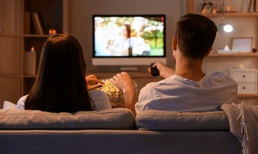 Couple with popcorn watching TV at home in evening