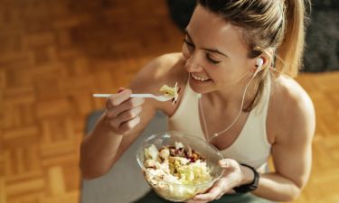 High angle view of athletic woman enjoying in healthy salad after sports training at home.