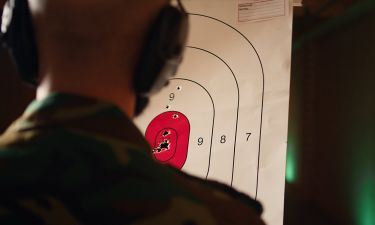 Man enjoying recreational shooting experience in firing range, checking if he shot bullseye. Person practicing with weapons in safe environment at shooting range company, hitting targets, camera A